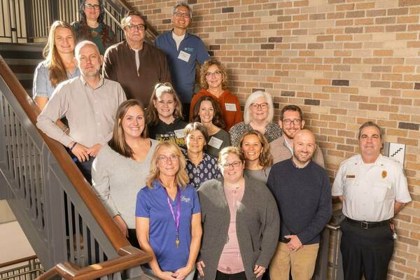 The attendees of the NDSI and Community Partners meeting stand on a staircase smiling